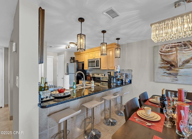 11619 Front Beach Rd Unit 1110, Panama City Beach, FL 32407 - kitchen featuring appliances with stainless steel finishes, light tile patterned flooring, backsplash, a breakfast bar area, and dark stone countertops