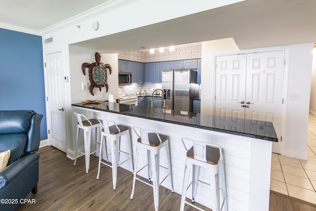 14701 Front Beach Rd Unit 1727, Panama City Beach, FL 32413 - kitchen with appliances with stainless steel finishes, a peninsula, ornamental molding, a kitchen breakfast bar, and open floor plan