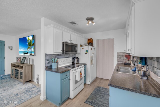 4331 Garrison Rd, Panama City, FL 32404 - kitchen featuring white appliances, dark countertops, light wood-style floors, white cabinetry, and decorative backsplash