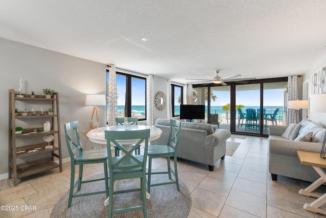6201 Thomas Dr Unit 202, Panama City Beach, FL 32408 - living room with a textured ceiling, a ceiling fan, a wall of windows, and baseboards