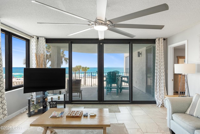 6201 Thomas Dr Unit 202, Panama City Beach, FL 32408 - living room with floor to ceiling windows, a textured ceiling, ceiling fan, baseboards, and tile patterned floors