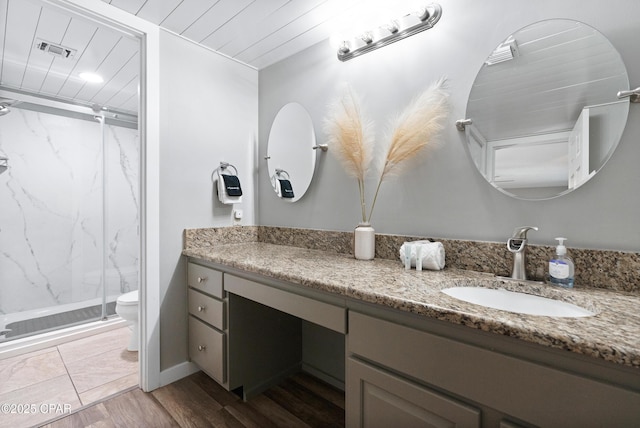 6201 Thomas Dr Unit 202, Panama City Beach, FL 32408 - bathroom featuring a marble finish shower, toilet, vanity, and wood finished floors