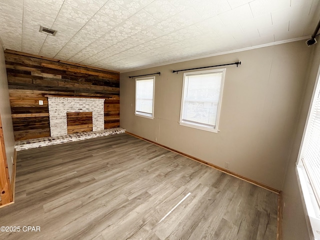811 Mcgee Rd, Bonifay, FL 32425 - unfurnished living room with wooden walls, crown molding, wood finished floors, a fireplace, and baseboards