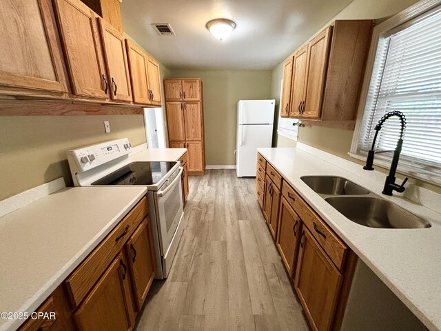 811 Mcgee Rd, Bonifay, FL 32425 - kitchen featuring white appliances, a sink, light wood-style floors, and light countertops