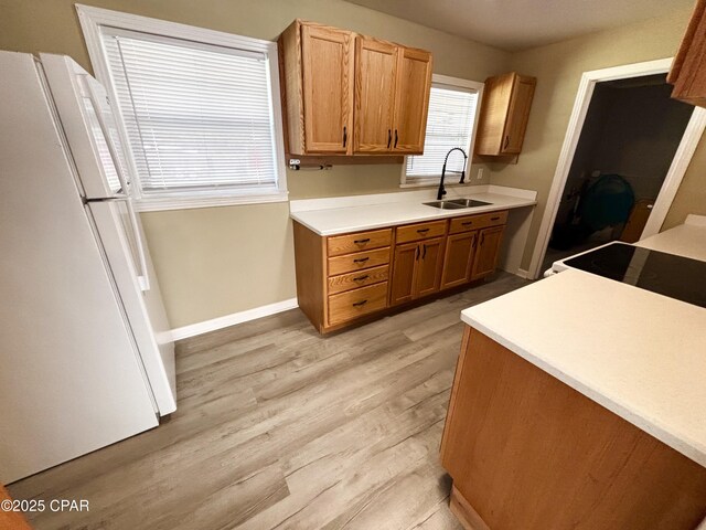811 Mcgee Rd, Bonifay, FL 32425 - kitchen with freestanding refrigerator, a sink, light wood-style flooring, stove, and light countertops