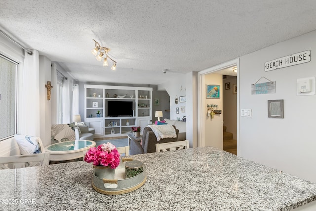 23223 Front Beach Rd Unit A704, Panama City Beach, FL 32413 - kitchen featuring a textured ceiling, track lighting, built in shelves, light stone countertops, and wood finished floors