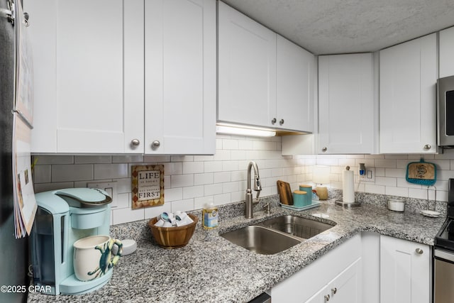 23223 Front Beach Rd Unit A704, Panama City Beach, FL 32413 - kitchen with a sink, white cabinets, decorative backsplash, and a textured ceiling