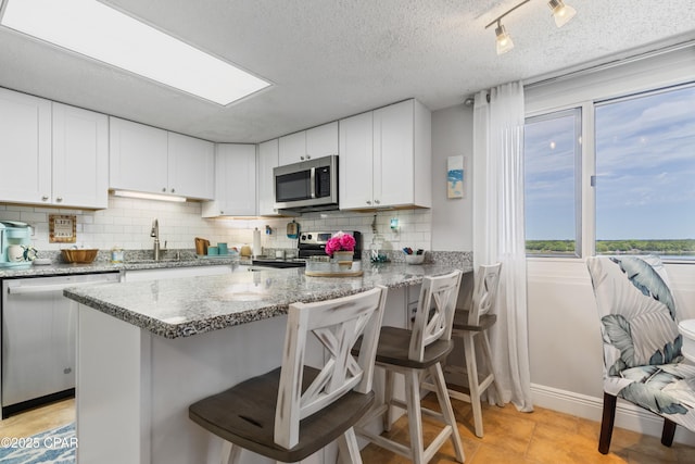 23223 Front Beach Rd Unit A704, Panama City Beach, FL 32413 - kitchen with stainless steel appliances, a sink, decorative backsplash, white cabinetry, and a textured ceiling