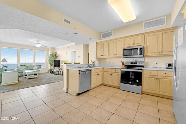8715 Surf Dr Unit 304B, Panama City, FL 32408 - kitchen featuring appliances with stainless steel finishes, a textured ceiling, open floor plan, light tile patterned floors, and a peninsula