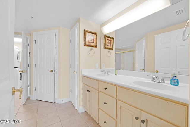 8715 Surf Dr Unit 304B, Panama City, FL 32408 - bathroom with stacked washing machine and dryer, tile patterned flooring, double vanity, and a shower with door