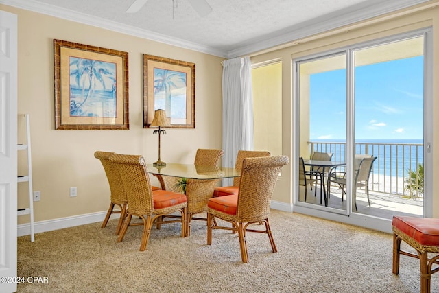 8715 Surf Dr Unit 304B, Panama City, FL 32408 - dining area featuring a water view, crown molding, carpet, a ceiling fan, and a textured ceiling