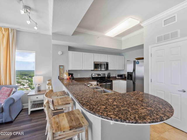 16819 Front Beach Rd Unit 2800, Panama City Beach, FL 32413 - kitchen featuring appliances with stainless steel finishes, ornamental molding, a peninsula, white cabinetry, and dark stone counters