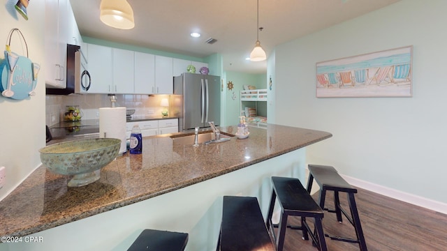 11800 Front Beach Rd Unit 2-201, Panama City Beach, FL 32407 - kitchen with appliances with stainless steel finishes, a peninsula, a breakfast bar, decorative backsplash, and white cabinetry