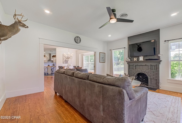 5138 8th Ave, Malone, FL 32445 - living room featuring light wood-style floors, a fireplace, a ceiling fan, a chandelier, and baseboards