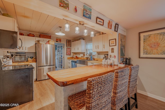 5821 S Lagoon Dr, Panama City, FL 32408 - kitchen featuring stainless steel appliances, a peninsula, light wood-style flooring, white cabinetry, and wooden ceiling