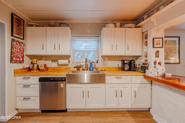 5821 S Lagoon Dr, Panama City, FL 32408 - kitchen with stainless steel dishwasher, a sink, light wood-style floors, white cabinets, and butcher block countertops