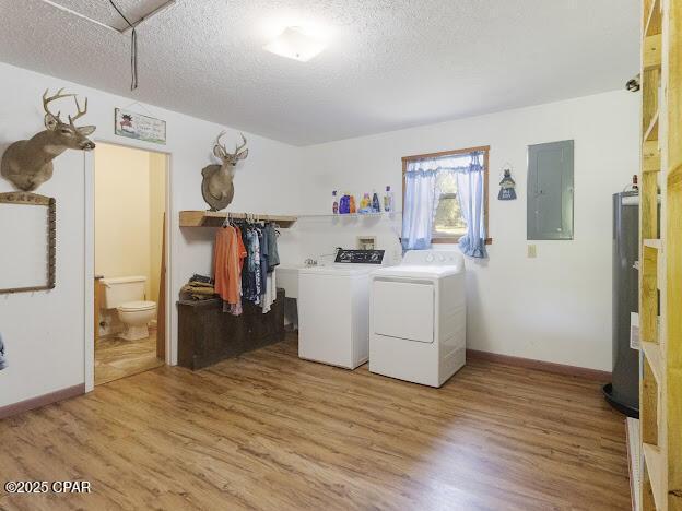 2921 Ambus Ln, Chipley, FL 32428 - laundry area featuring electric panel, washing machine and clothes dryer, a textured ceiling, light wood-style flooring, and water heater