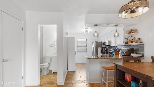 612 Laurel St Unit D, Panama City Beach, FL 32407 - kitchen featuring stainless steel appliances, open shelves, white cabinets, a peninsula, and light tile patterned flooring