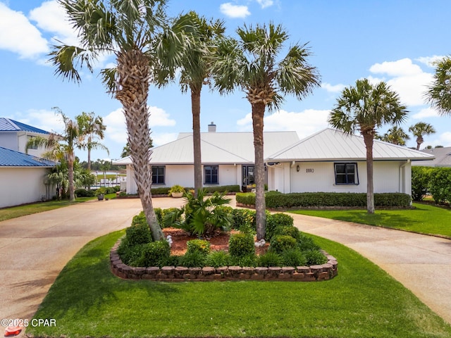 1110 Redfish Cir, Panama City, FL 32408 - ranch-style house with curved driveway, a chimney, a front yard, metal roof, and a standing seam roof