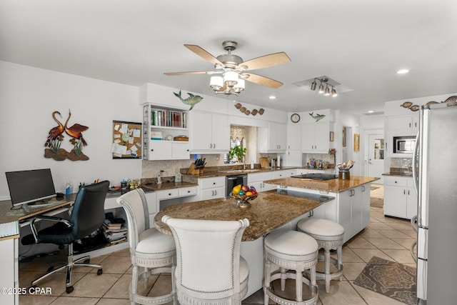 1110 Redfish Cir, Panama City, FL 32408 - kitchen with appliances with stainless steel finishes, a center island, decorative backsplash, a ceiling fan, and white cabinets