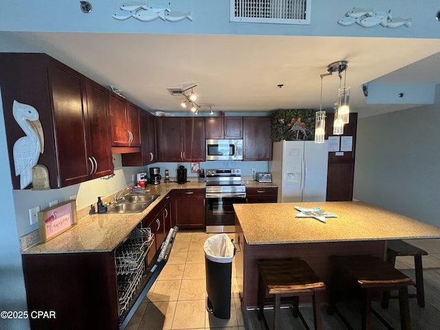 9902 S Thomas Dr Unit 636, Panama City Beach, FL 32408 - kitchen featuring stainless steel appliances, a sink, a breakfast bar area, hanging light fixtures, and light tile patterned flooring
