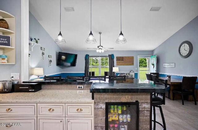 21382 NW Paradise Ln, Altha, FL 32421 - kitchen with beverage cooler, ceiling fan, vaulted ceiling, light stone countertops, and hanging light fixtures