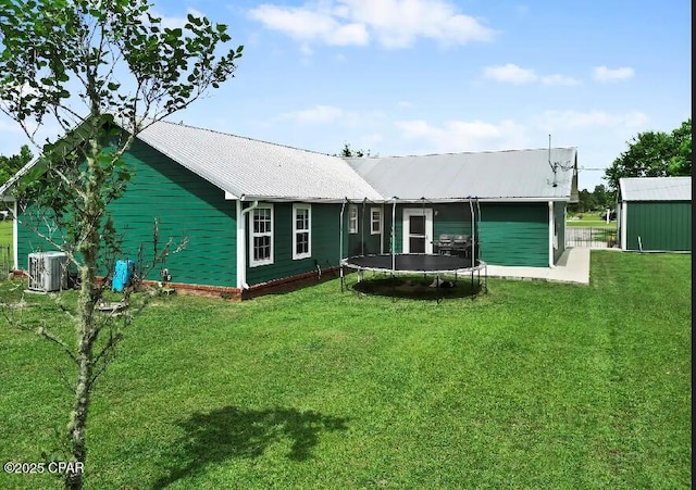 21382 NW Paradise Ln, Altha, FL 32421 - back of house with a trampoline, a yard, metal roof, and central AC
