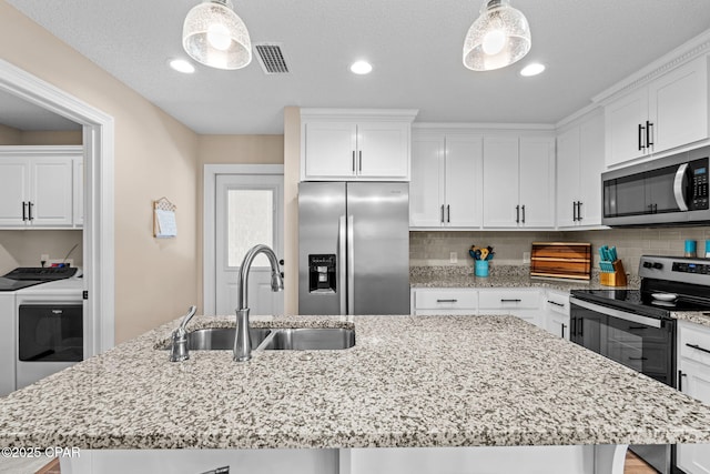 4304 Bylsma Cir, Panama City, FL 32404 - kitchen featuring stainless steel appliances, washer and dryer, a sink, an island with sink, and tasteful backsplash