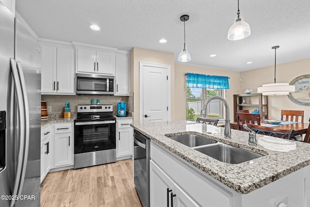 4304 Bylsma Cir, Panama City, FL 32404 - kitchen with stainless steel appliances, a sink, light wood-style floors, white cabinetry, and tasteful backsplash
