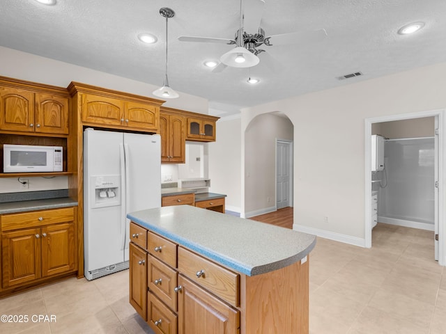 1406 New Jersey Ave, Lynn Haven, FL 32444 - kitchen with white appliances, a ceiling fan, arched walkways, brown cabinets, and a center island