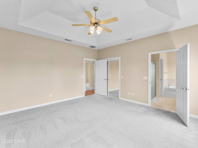 1406 New Jersey Ave, Lynn Haven, FL 32444 - unfurnished bedroom featuring light colored carpet, baseboards, ensuite bathroom, ceiling fan, and a raised ceiling