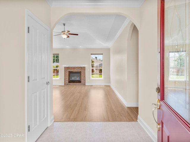1406 New Jersey Ave, Lynn Haven, FL 32444 - unfurnished living room featuring ceiling fan, ornamental molding, a glass covered fireplace, arched walkways, and baseboards