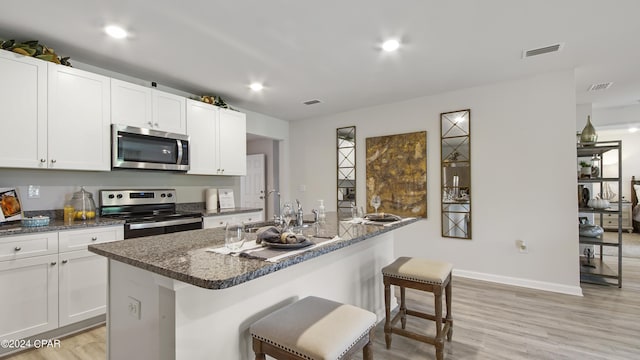 4132 Concord Blvd, Chipley, FL 32428 - kitchen featuring stainless steel appliances, light wood-style floors, white cabinetry, a sink, and a kitchen breakfast bar