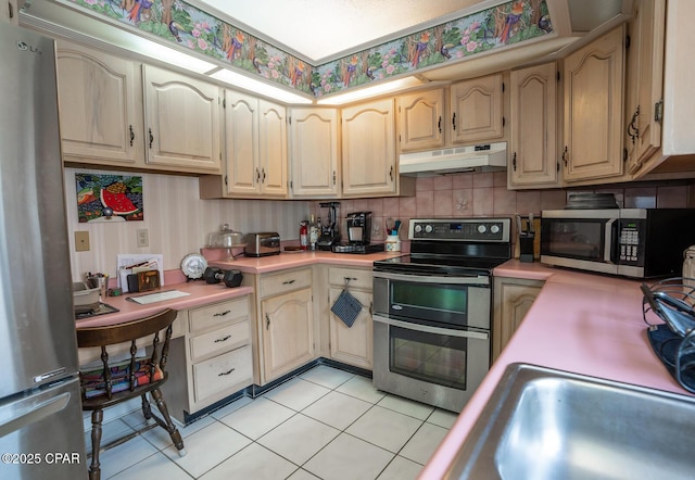 2712 Woodmere Dr, Panama City, FL 32405 - kitchen with appliances with stainless steel finishes, under cabinet range hood, light countertops, light tile patterned floors, and a sink