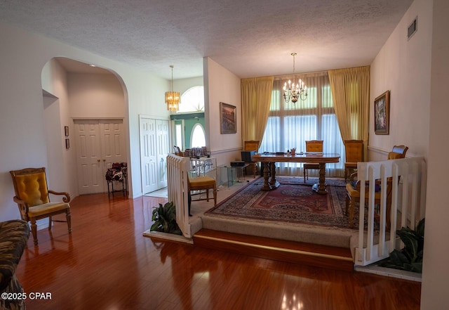2712 Woodmere Dr, Panama City, FL 32405 - dining area featuring wood finished floors, a chandelier, a textured ceiling, and arched walkways