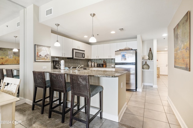 11807 Front Beach Rd Unit 1-706, Panama City Beach, FL 32407 - kitchen with stainless steel appliances, a peninsula, stone counters, decorative backsplash, and white cabinetry