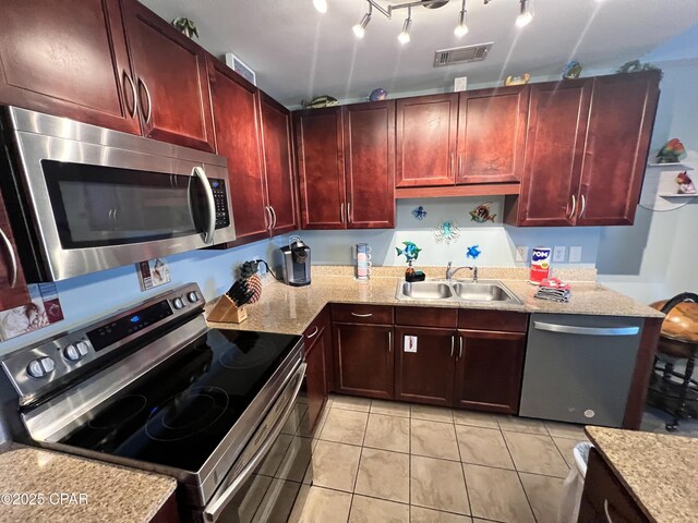 9902 S Thomas Dr Unit 237, Panama City Beach, FL 32408 - kitchen with stainless steel appliances, reddish brown cabinets, a sink, and light tile patterned floors