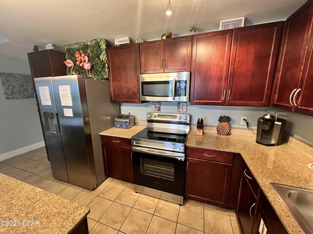 9902 S Thomas Dr Unit 237, Panama City Beach, FL 32408 - kitchen with appliances with stainless steel finishes, dark brown cabinets, light tile patterned floors, a sink, and light stone counters