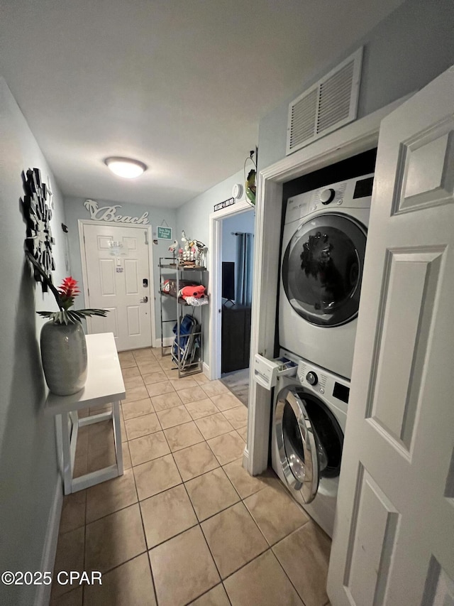 9902 S Thomas Dr Unit 237, Panama City Beach, FL 32408 - washroom with stacked washer and clothes dryer, light tile patterned flooring, and baseboards