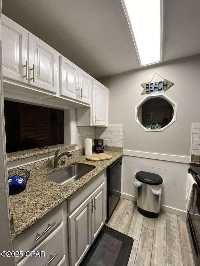 17214 Front Beach Rd Unit G-4, Panama City Beach, FL 32413 - kitchen featuring black dishwasher, a sink, light wood-style flooring, white cabinets, and light stone counters