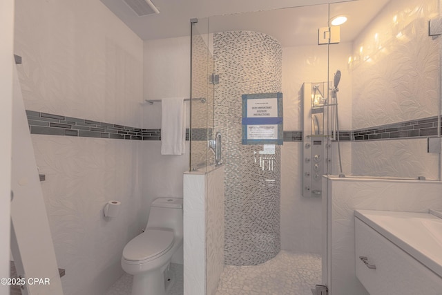 17735 Front Beach Rd Unit 2, Panama City Beach, FL 32413 - bathroom with tiled shower, vanity, toilet, and tile walls