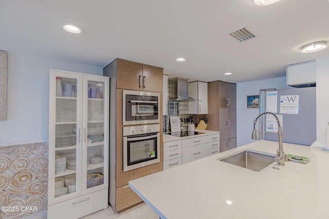 17735 Front Beach Rd Unit 2, Panama City Beach, FL 32413 - kitchen with wall chimney range hood, a sink, light countertops, stainless steel double oven, and recessed lighting