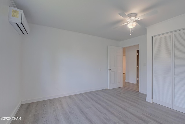 25966 George Maloy Ln, Altha, FL 32421 - unfurnished bedroom with a wall mounted air conditioner, light wood-style floors, a closet, and baseboards
