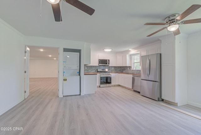 25966 George Maloy Ln, Altha, FL 32421 - kitchen featuring appliances with stainless steel finishes, a ceiling fan, stacked washing machine and dryer, ornamental molding, and light wood-style flooring