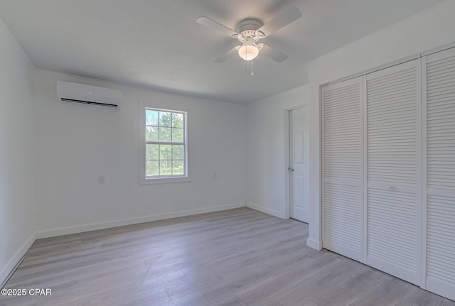 25966 George Maloy Ln, Altha, FL 32421 - unfurnished bedroom with a wall mounted air conditioner, light wood-type flooring, a closet, and baseboards