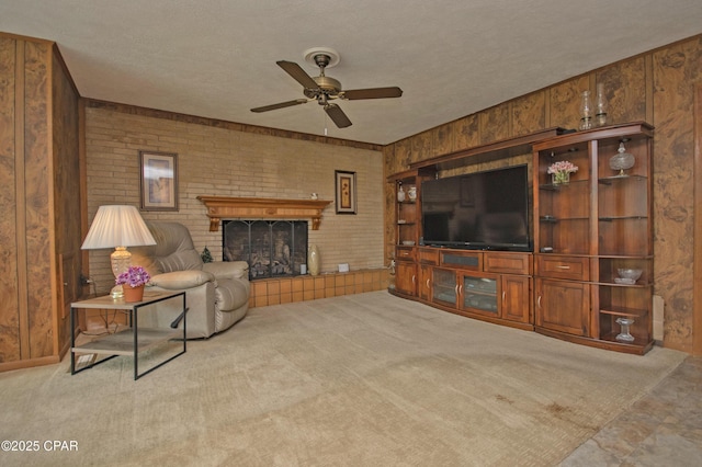 1206 Tyndall Dr, Panama City, FL 32401 - carpeted living room with ceiling fan, wooden walls, a fireplace, a textured ceiling, and brick wall