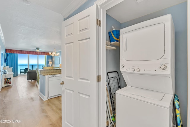 17545 Front Beach Rd Unit 2004, Panama City Beach, FL 32413 - washroom featuring stacked washer and clothes dryer, light wood-style flooring, ceiling fan, crown molding, and a chandelier