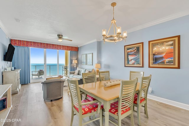 17545 Front Beach Rd Unit 2004, Panama City Beach, FL 32413 - dining space featuring crown molding, light wood finished floors, a chandelier, a ceiling fan, and a water view