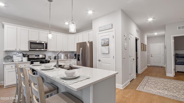 113 Mosaic Dr, Port St Joe, FL 32456 - kitchen featuring stainless steel appliances, a sink, light wood-type flooring, a breakfast bar area, and decorative backsplash