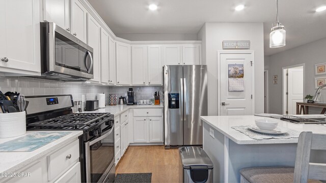 113 Mosaic Dr, Port St Joe, FL 32456 - kitchen featuring stainless steel appliances, white cabinetry, light wood-style floors, and tasteful backsplash